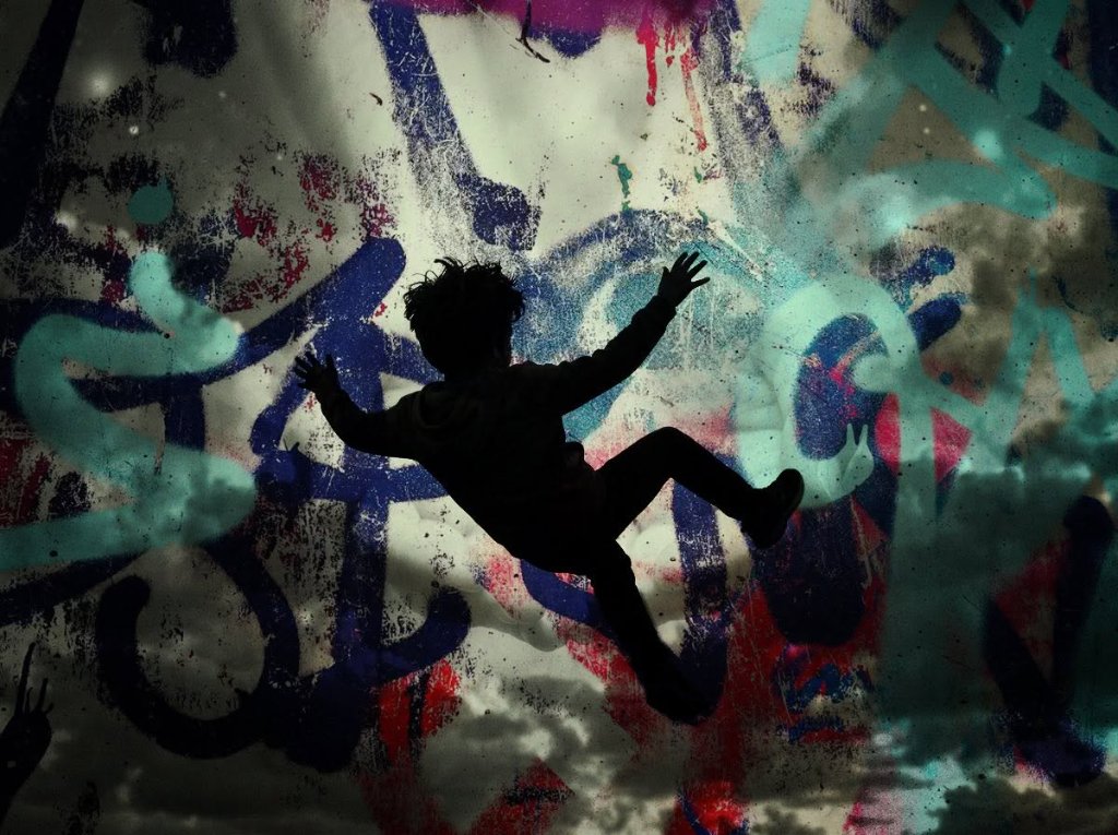 Boy silhouette falling against a colorful graffiti mural