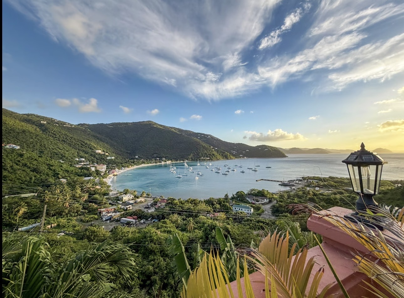 Calm bay ringed by green hills at golden hour in the British Virgin Islands
