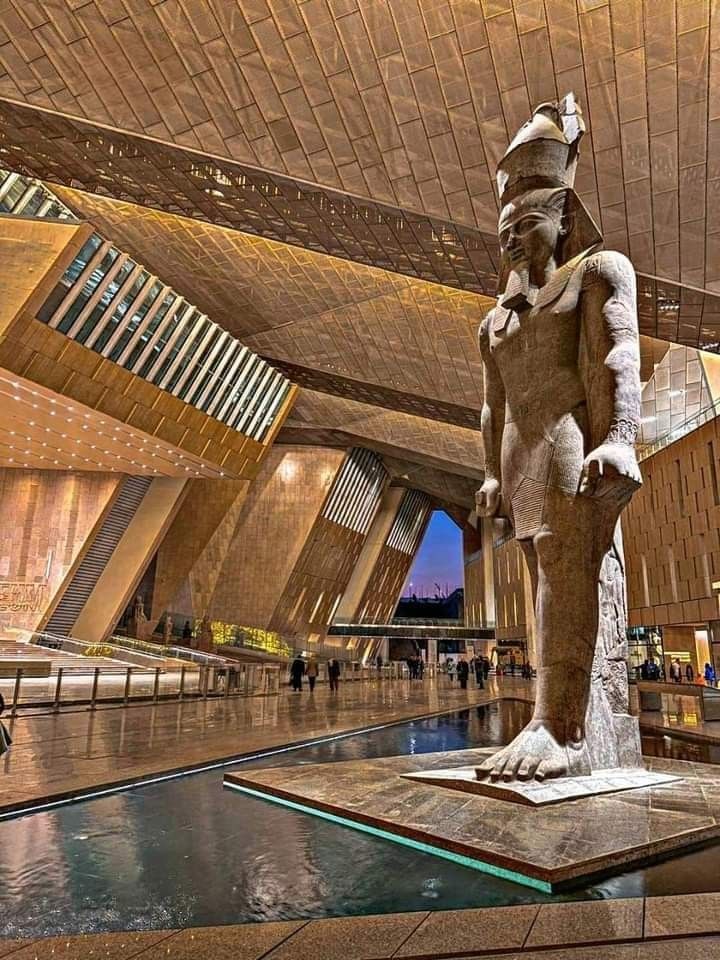 Grand Egyptian Museum interior with Ramesses II statue at dusk