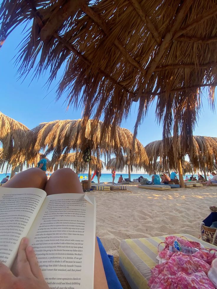 Reading a book on the beach under thatched palm umbrellas