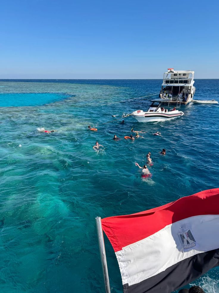 Snorkellers in turquoise Red Sea water with a tour boat