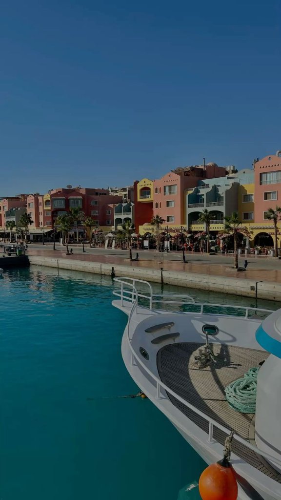 Yacht docked at Hurghada marina with colourful buildings