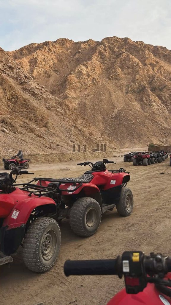 Red quad bikes lined up on a rocky desert mountain trail