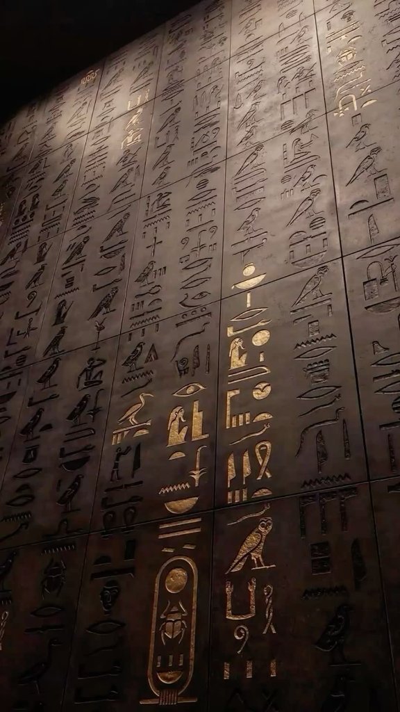 Ancient Egyptian hieroglyphics carved on golden wall panels