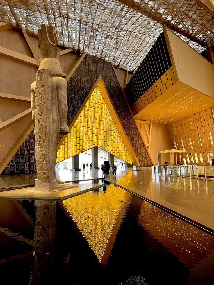 Grand Egyptian Museum golden hall with ancient statue reflected in water