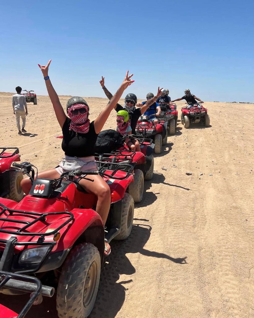 Group of riders on red quad bikes in the desert