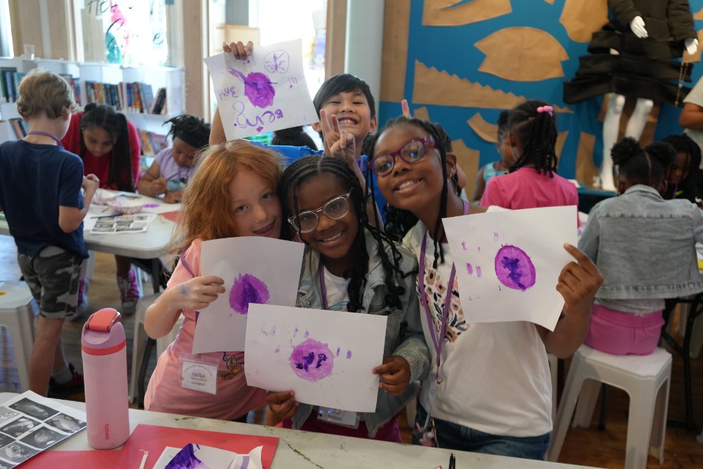 Summer campers proudly holding up their paintings