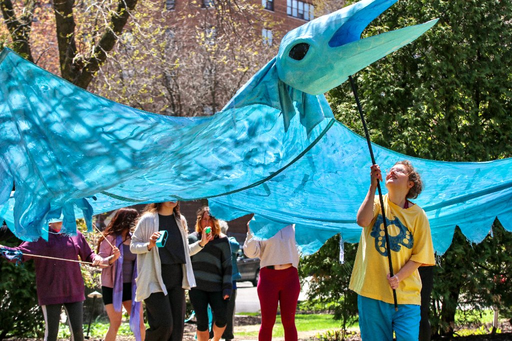 Community member holding a giant blue bird puppet at the Bird Parade