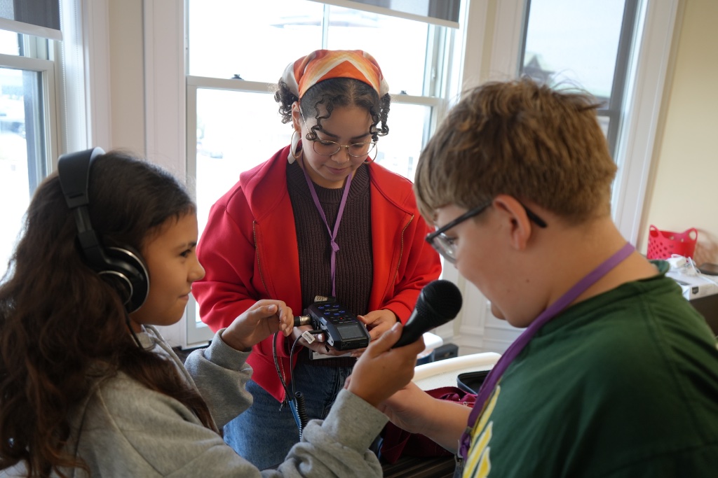 Youth recording audio with a handheld recorder and microphone