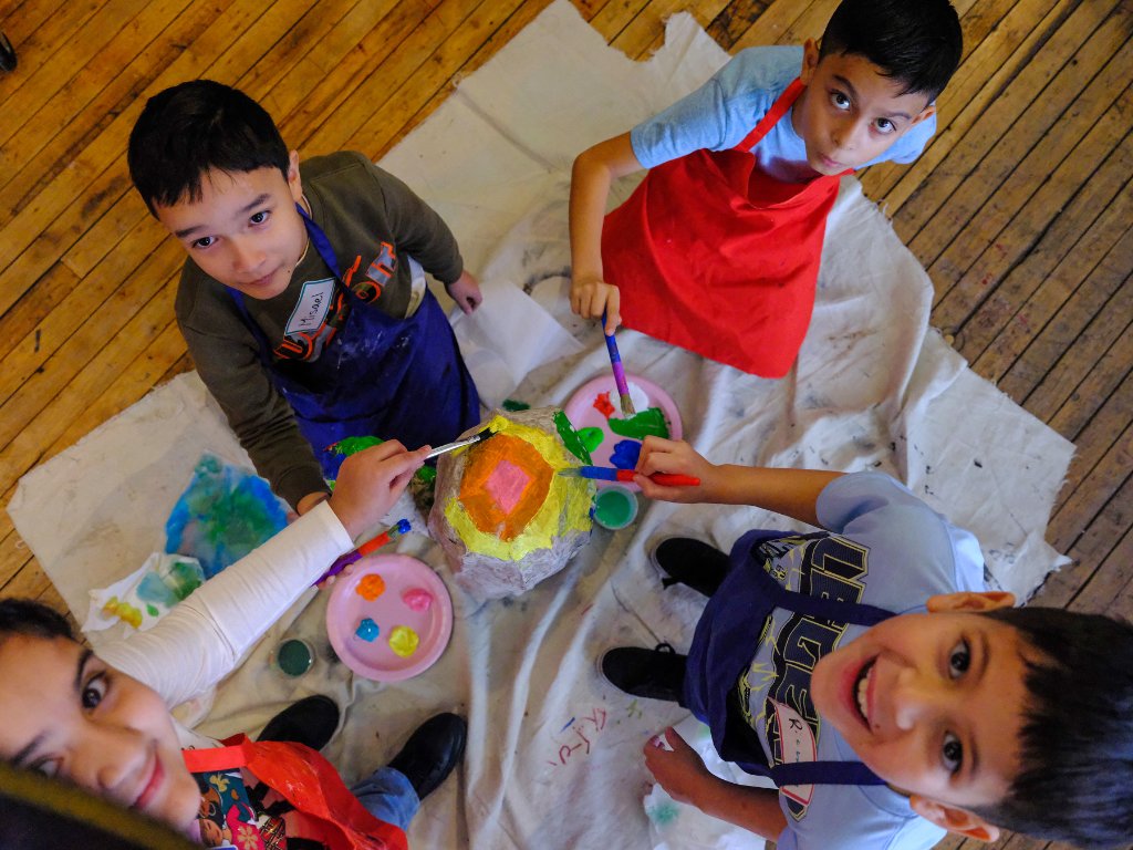 Overhead view of children painting a papier-mâché sculpture