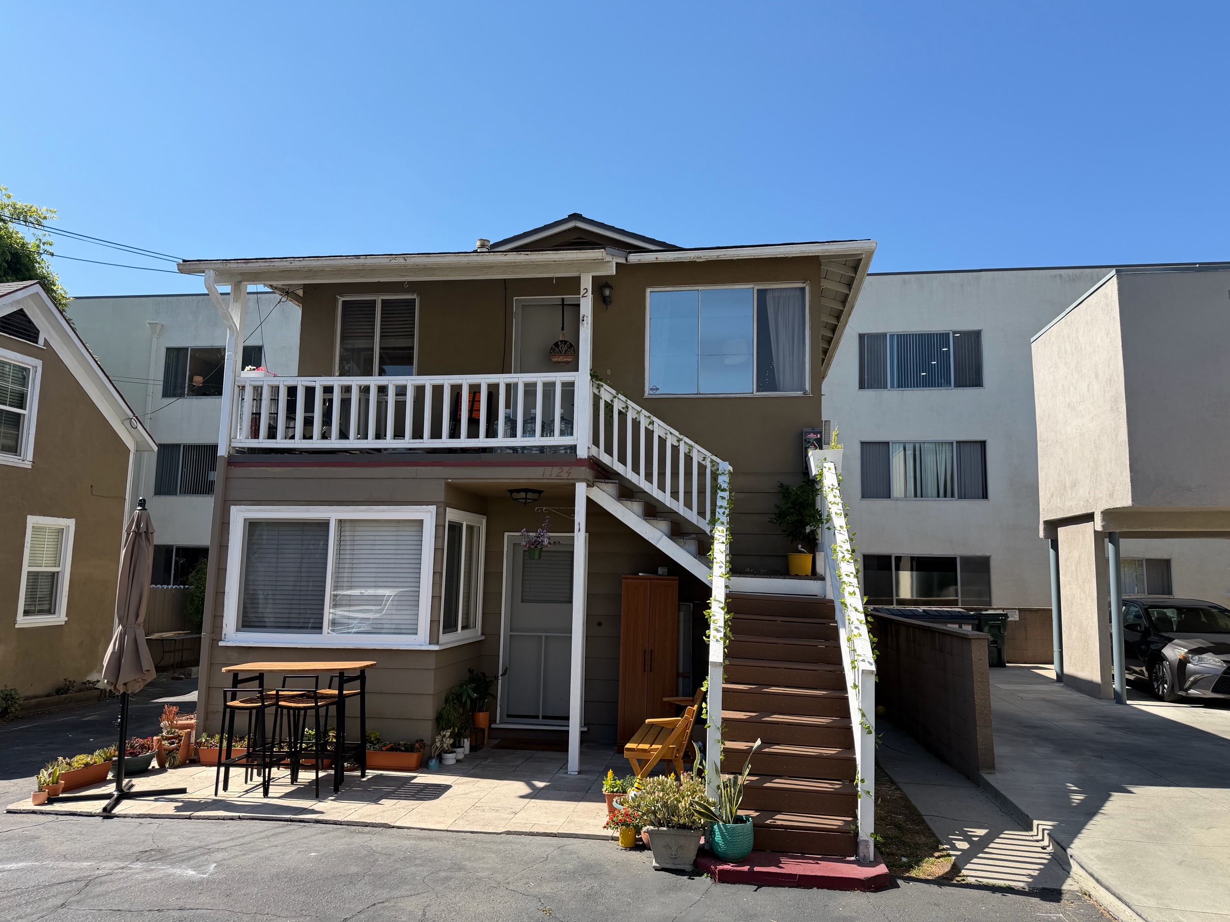 Multi-level stucco home with exterior staircase and patio