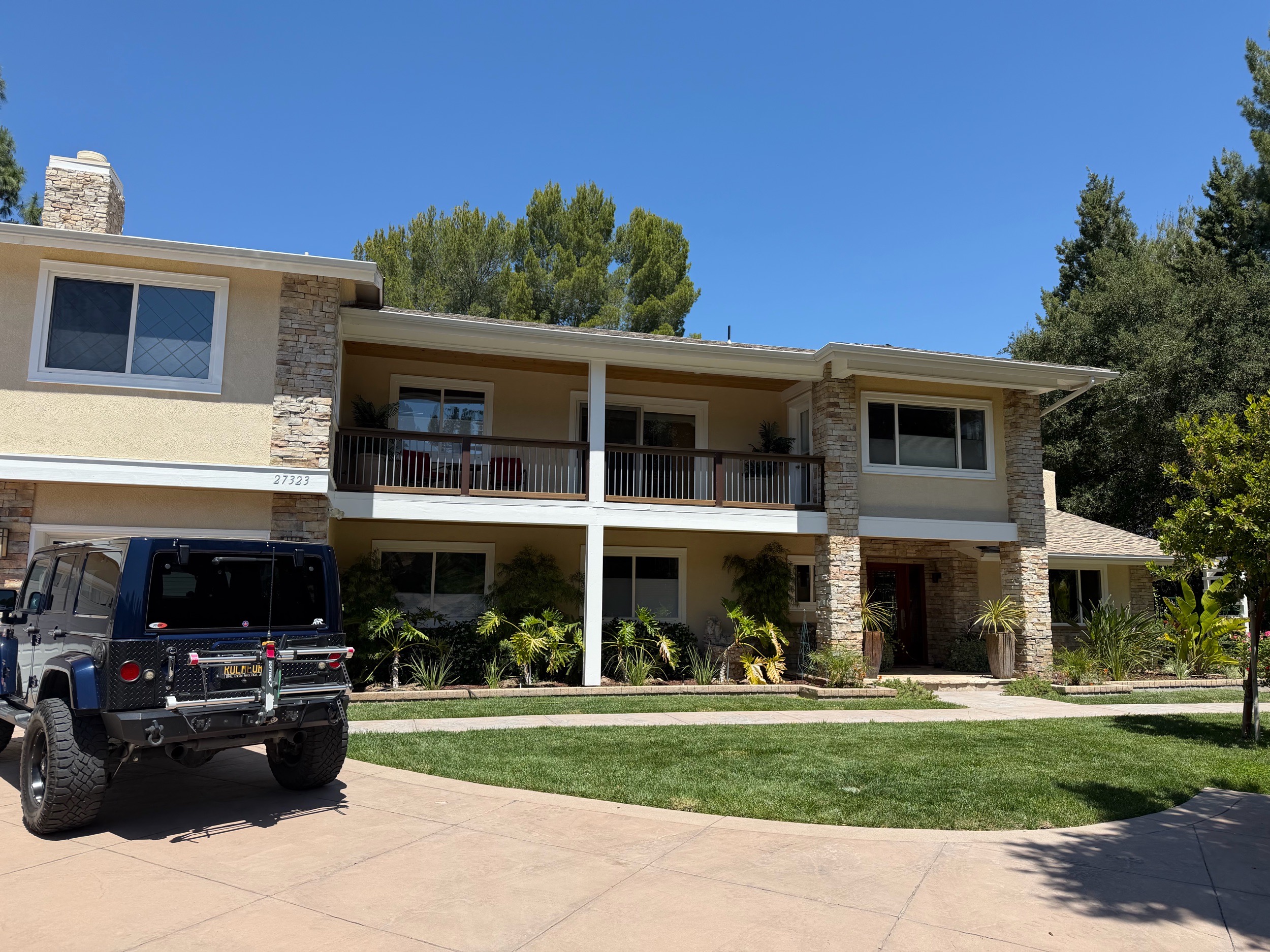 Two-story stucco home with stone accents and second-floor balcony