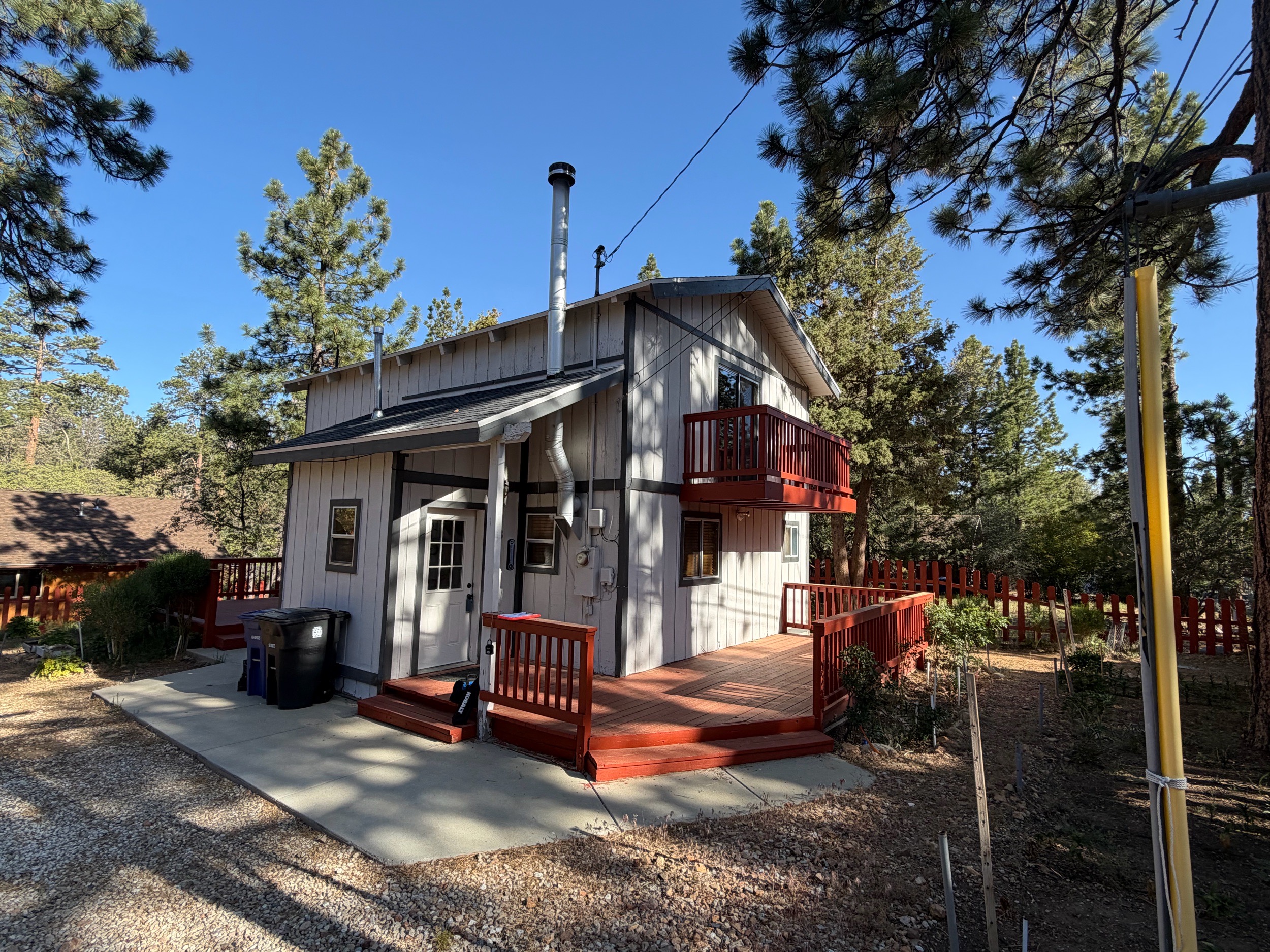Two-story cabin-style home with upper balcony in the pines