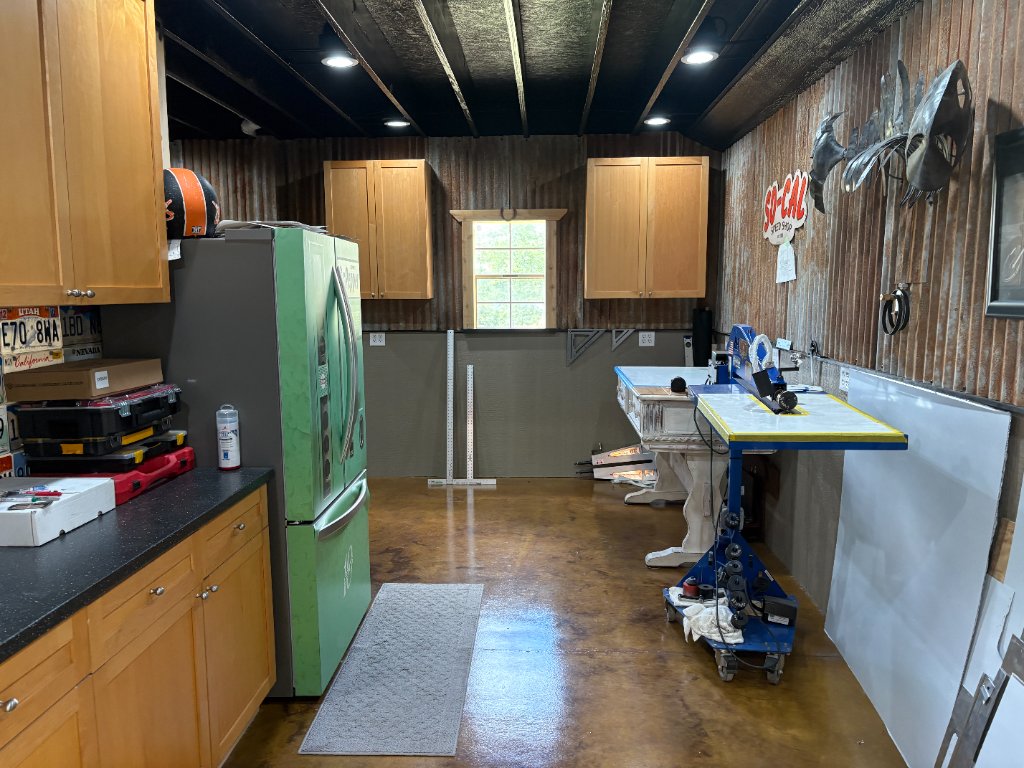 Kitchen — license plate backsplash, wood cabinets, retro fridge, view into the shop