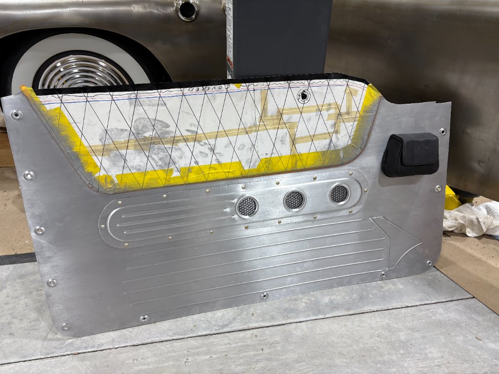 Bare aluminum panel — riveted speaker grilles, bead-rolled speed lines, window regulator pocket