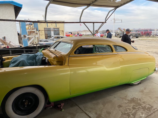 Patina sedan — rust and chrome, open hood, sunset backdrop