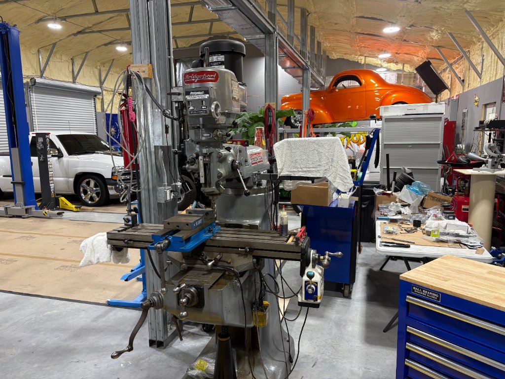 Bridgeport knee mill — precision machining with the orange Willys overhead