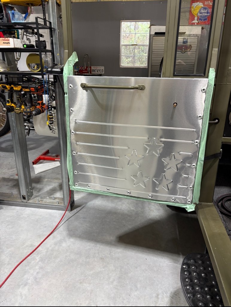 Door panel before paint — bare aluminum with bead-rolled speed lines and star stampings