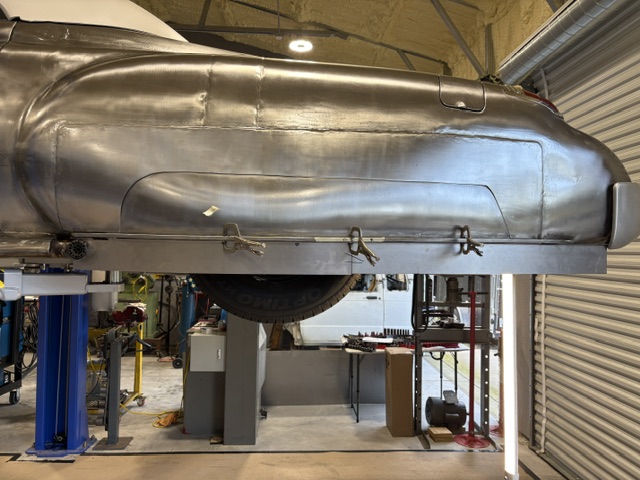 Underside view — rear quarter extension in bare metal on the lift