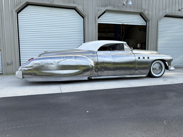 Driver's side profile — bare metal roadster stance on the apron