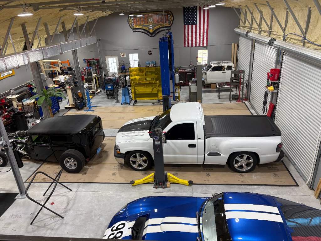 Wayne's Rods West — full shop floor, American flag, multiple builds underway