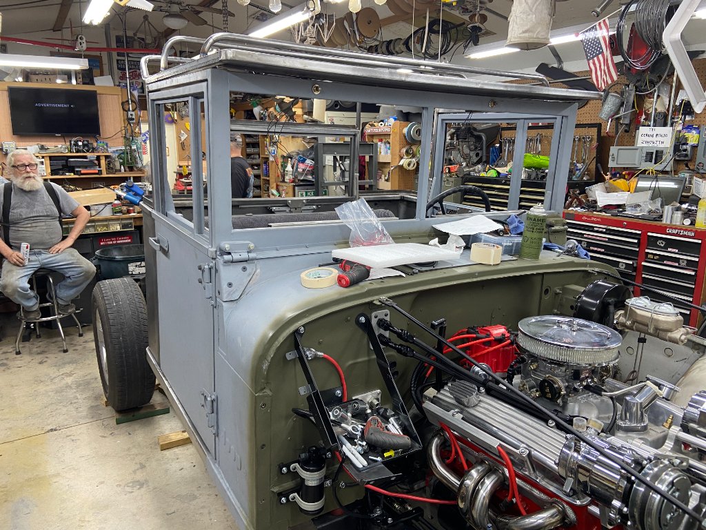 Before — engine bay exposed, glass frames mocked up, builder at work