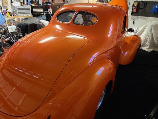 Driver's side profile — flawless orange paint, smoothed body, killer stance