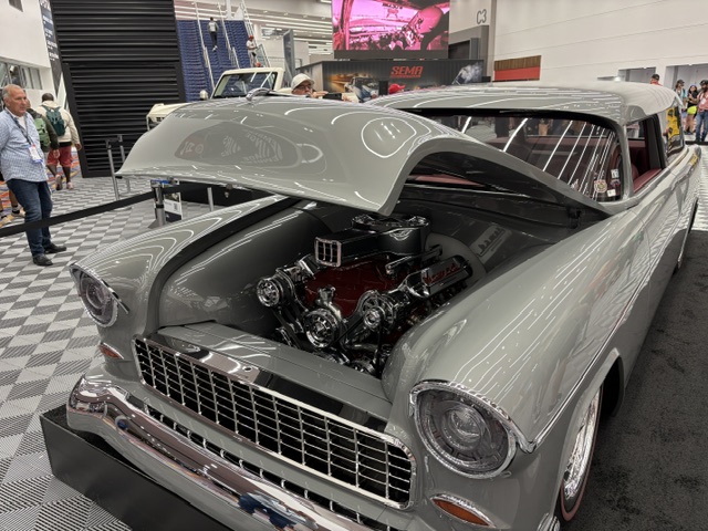 Gray 1955 Chevy — open hood, small block V8, SEMA show floor