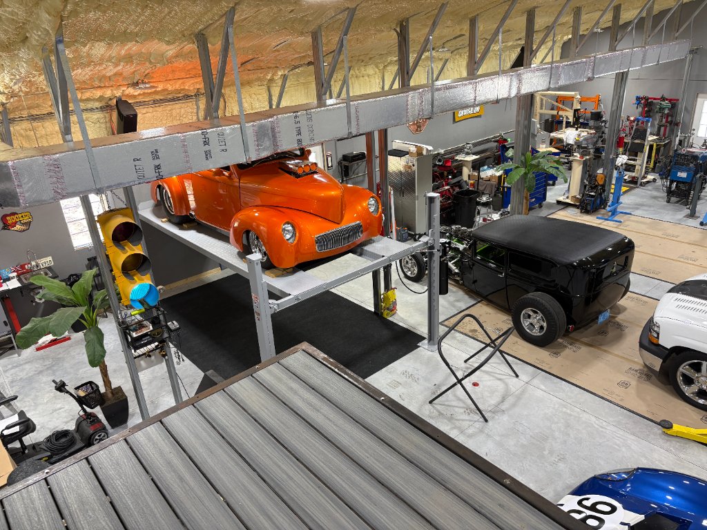 Shop overview — orange Willys on the lift, 1931 coupe and builds in progress