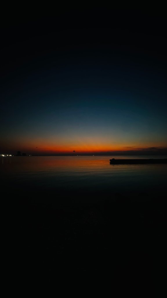 A deep orange and blue sunset reflected on still water