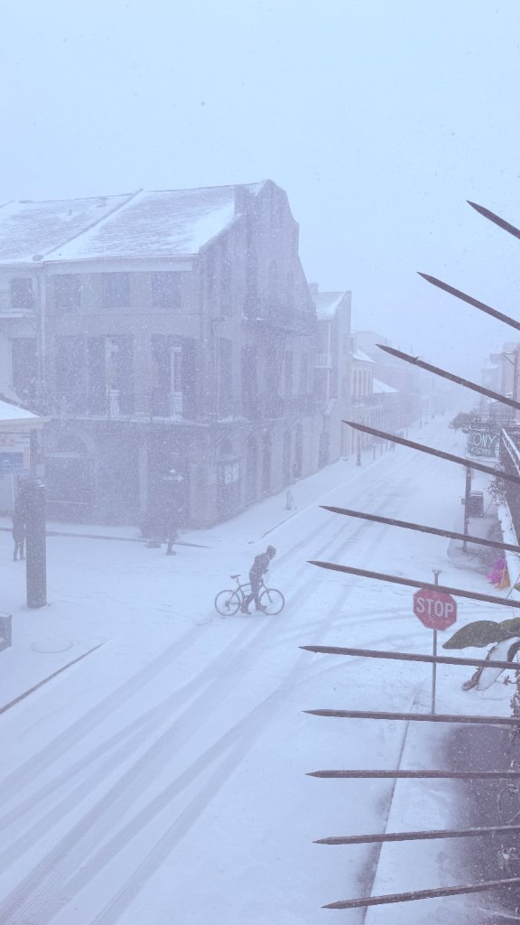 A lone cyclist crosses a snow-covered New Orleans street during a rare blizzard