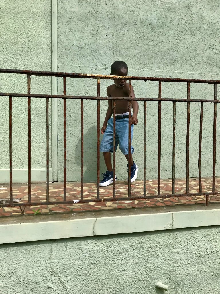 A young boy walking along an iron fence on a New Orleans street