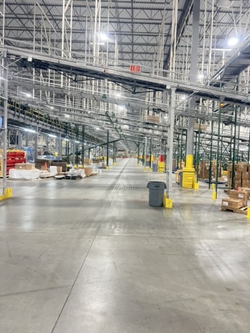 Warehouse facility before and after an ecoZohm LED upgrade — Aisle under overhead conveyor — after
