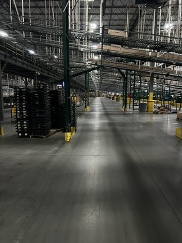 Warehouse facility before and after an ecoZohm LED upgrade — Aisle under overhead conveyor — before