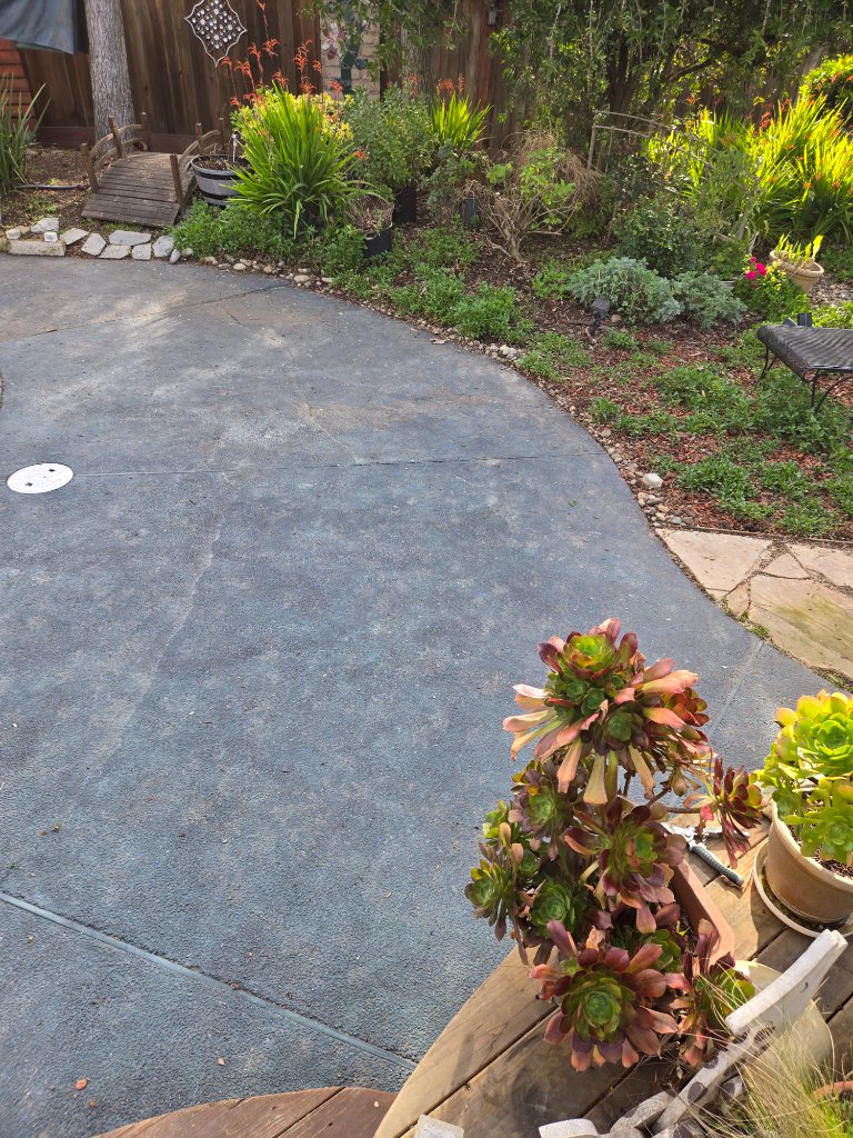 Worker finishing concrete patio by shed