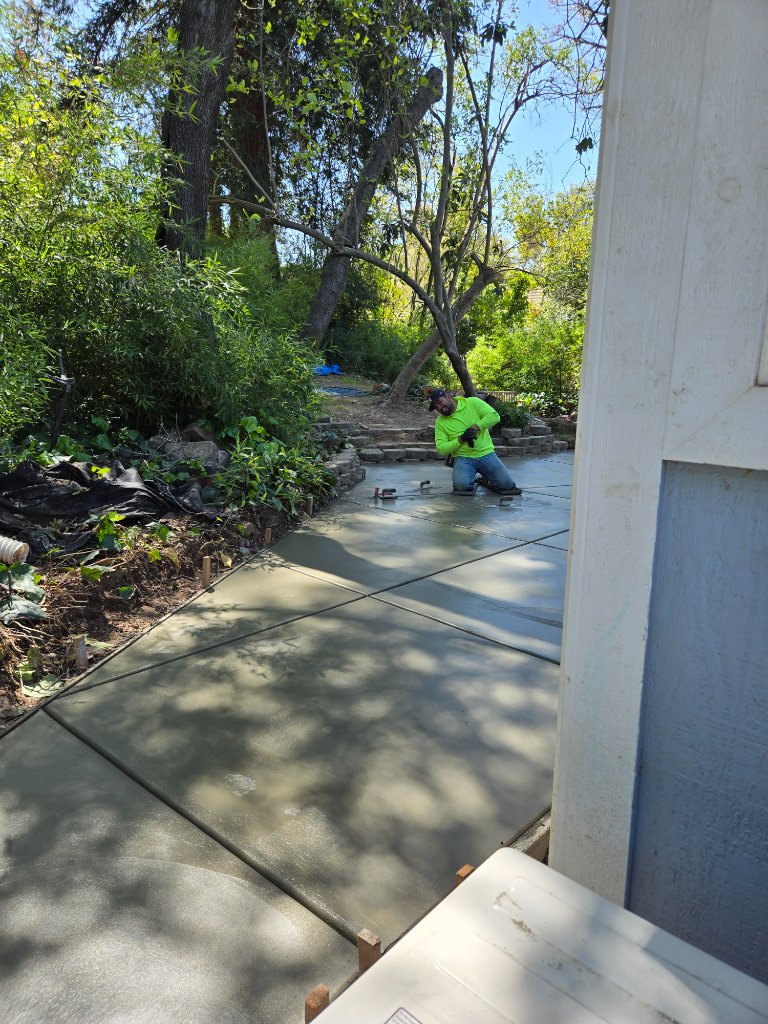 Worker finishing concrete patio near garden