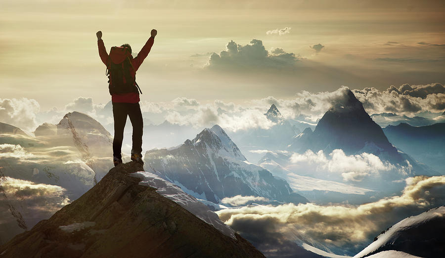 Mountaineer on a mountain summit at sunrise