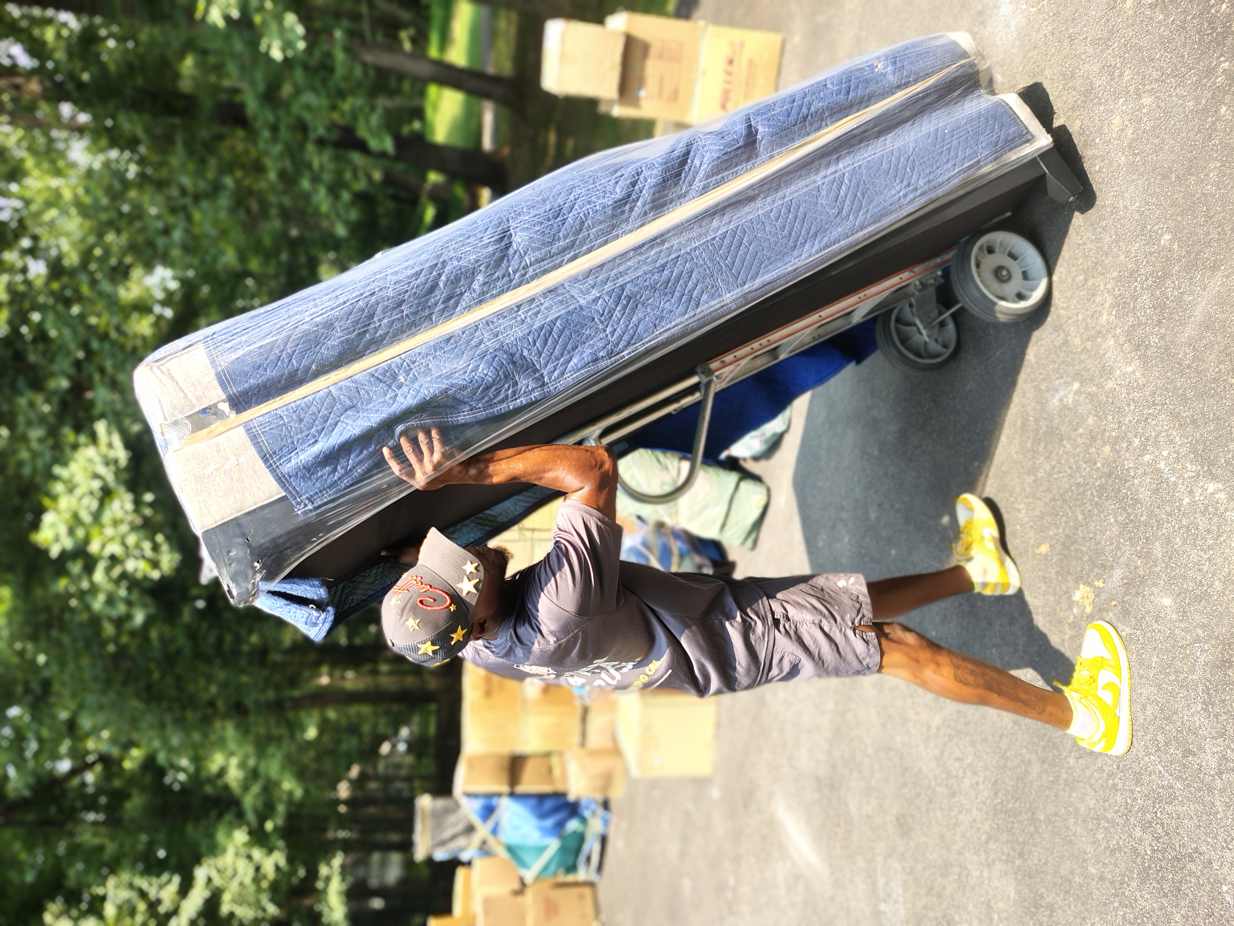 Relocation Technician transporting a furniture piece wrapped in a moving blanket on a dolly