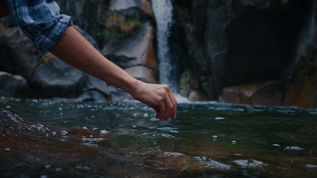 Woman touching mountain waterfall pool