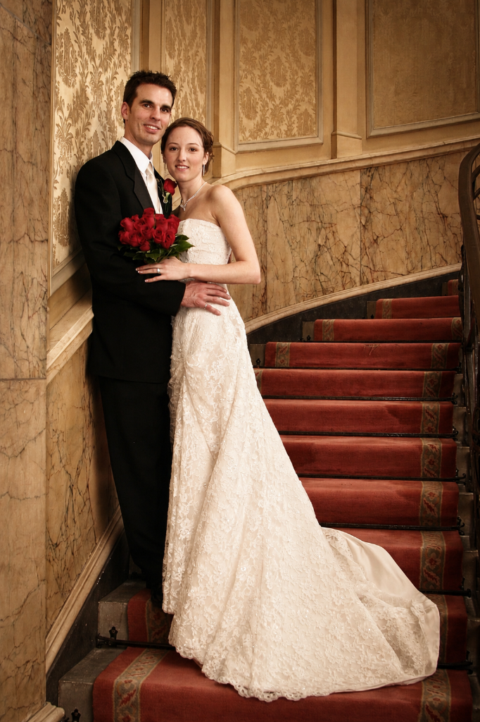 Daniel & Nicole wedding portrait on grand staircase with red rose bouquet