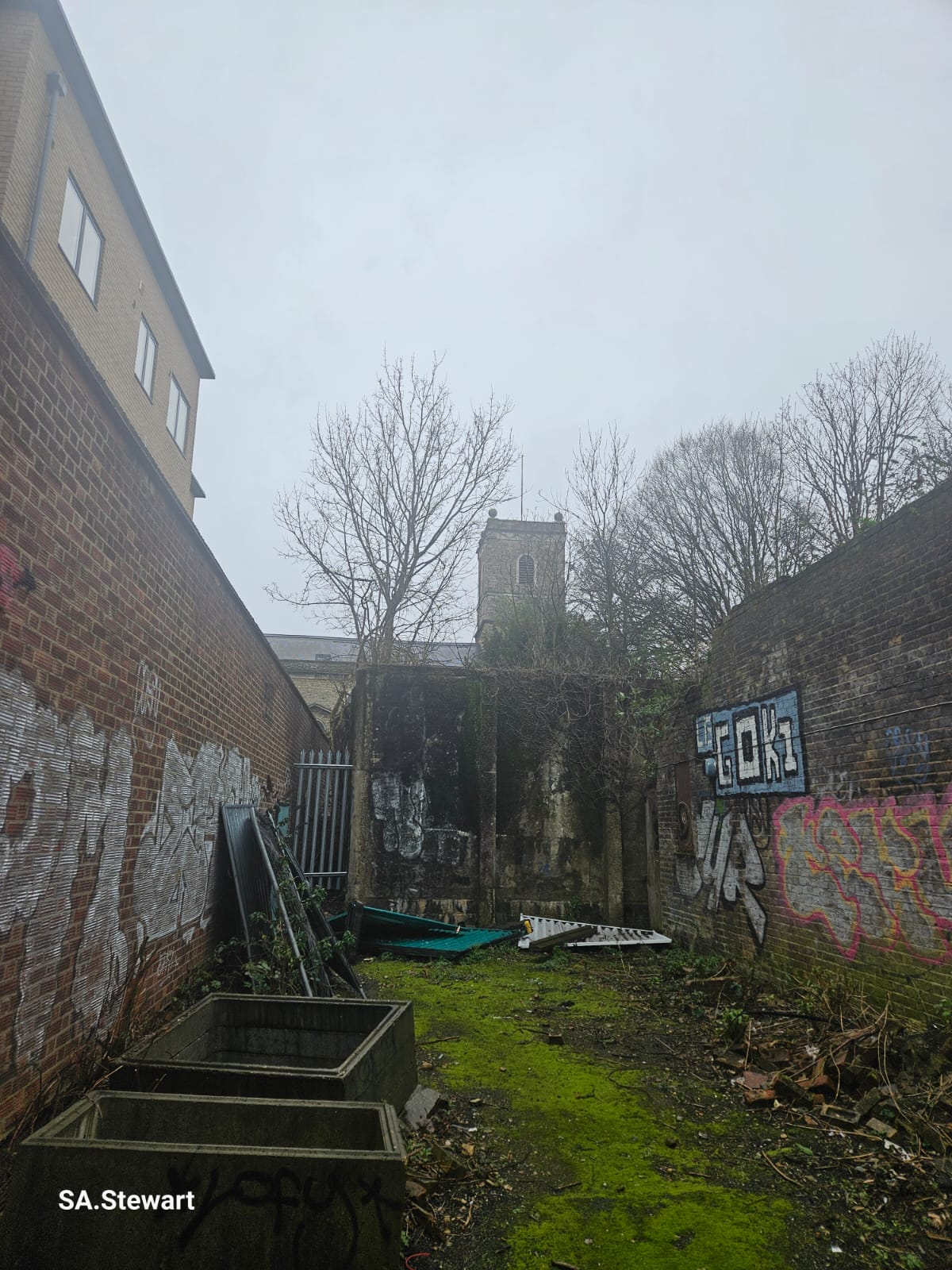 The side courtyard, with graffiti covered brick walls and the historic tower beyond