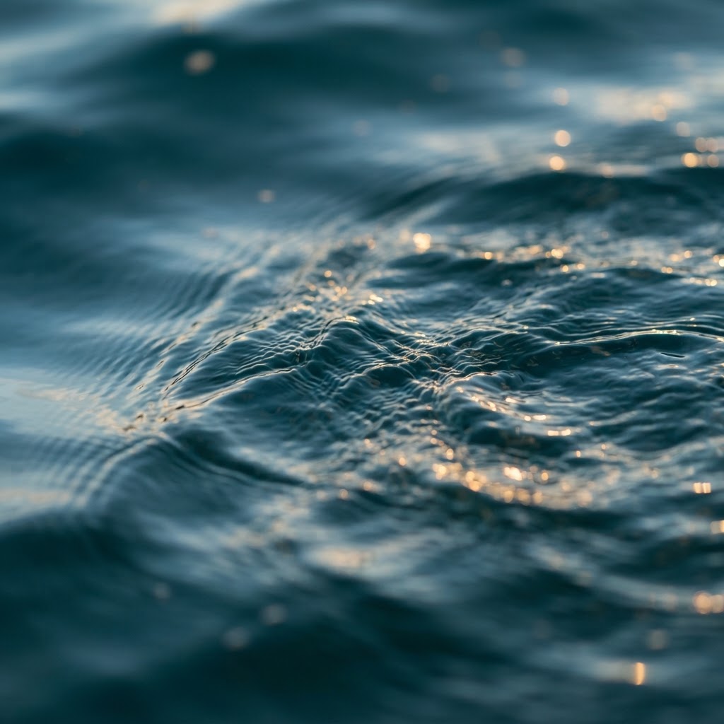 Gentle water ripples in deep teal with warm gold light reflections