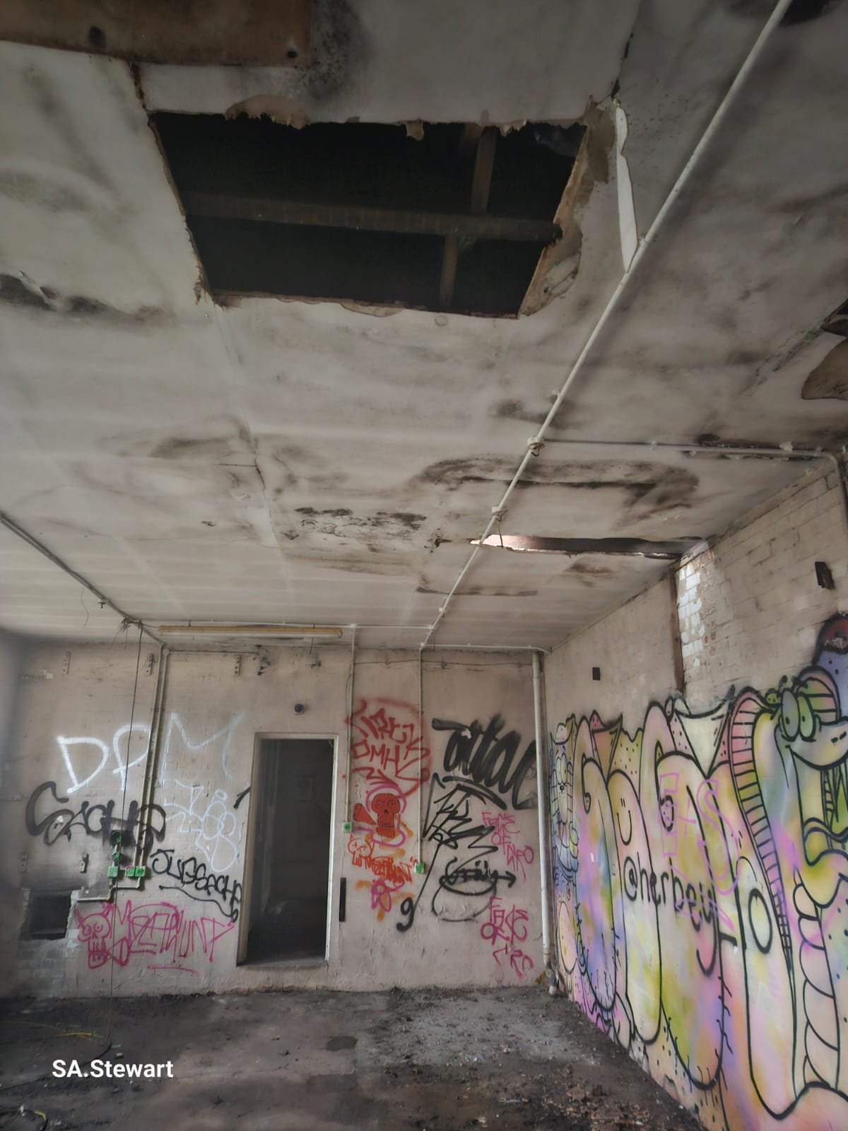 A small interior room with a collapsed ceiling and vivid graffiti murals