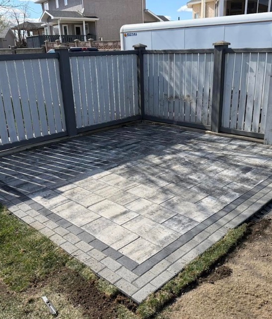 Clean paving stone patio inside a fenced backyard