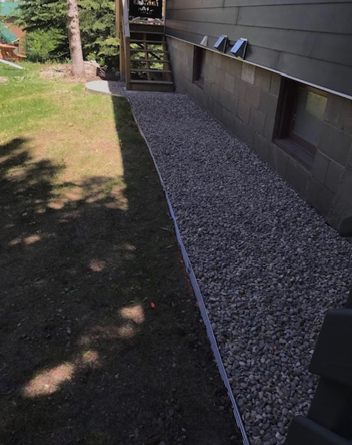 Clean gravel landscape bed beside a home with edging and lawn