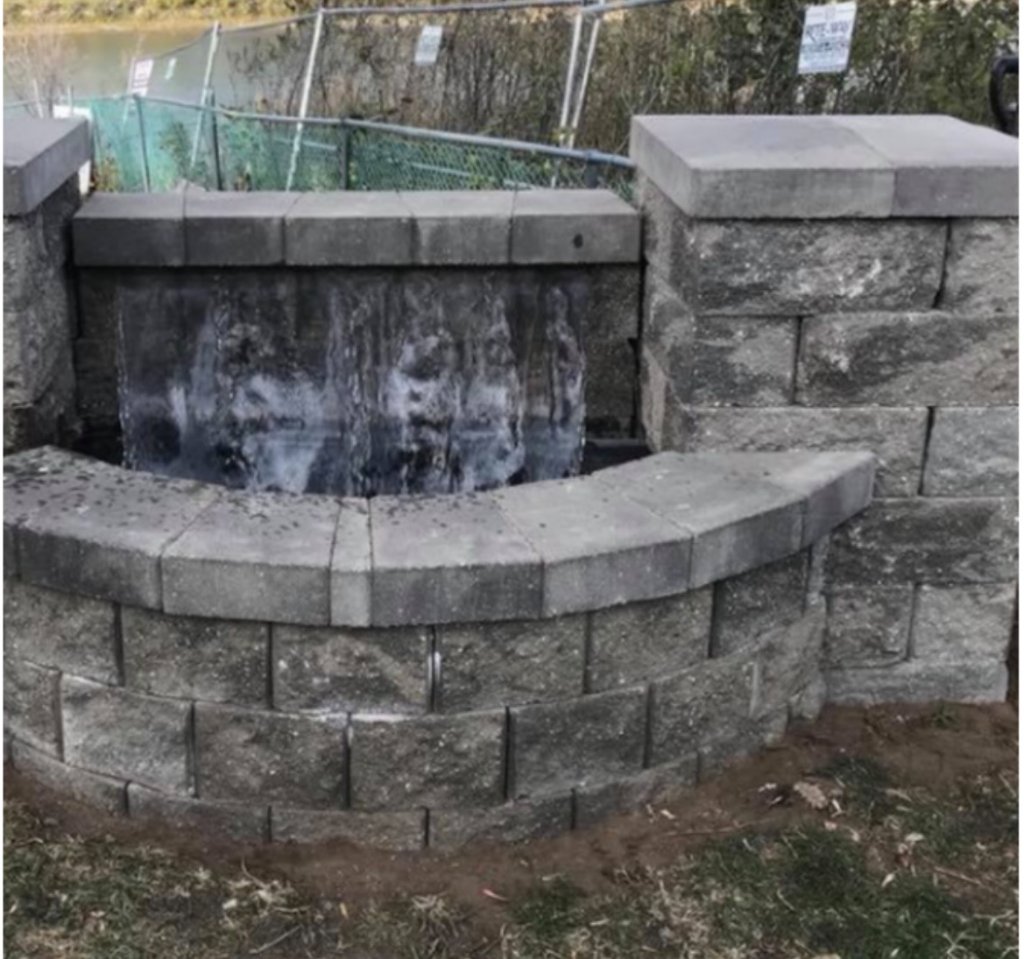 Curved stone water feature with retaining wall blocks and cap stones