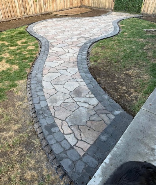 Curved decorative paving stone pathway with dark stone border