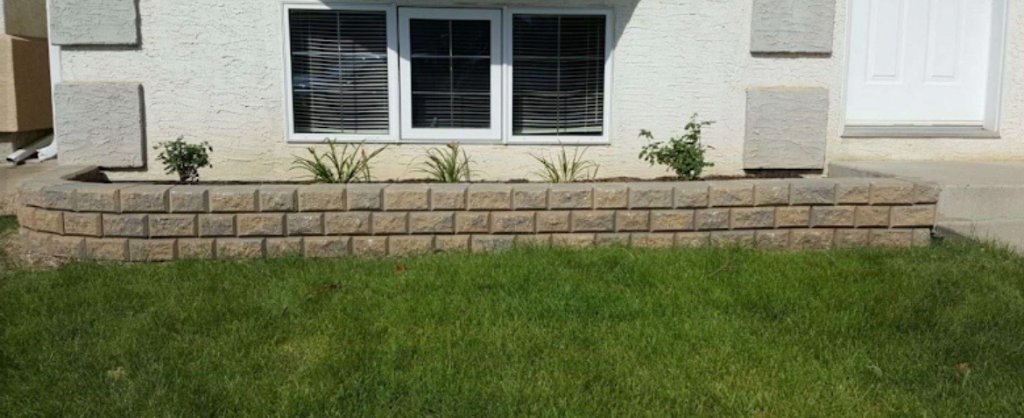 Low retaining wall and planting bed below front windows with green lawn