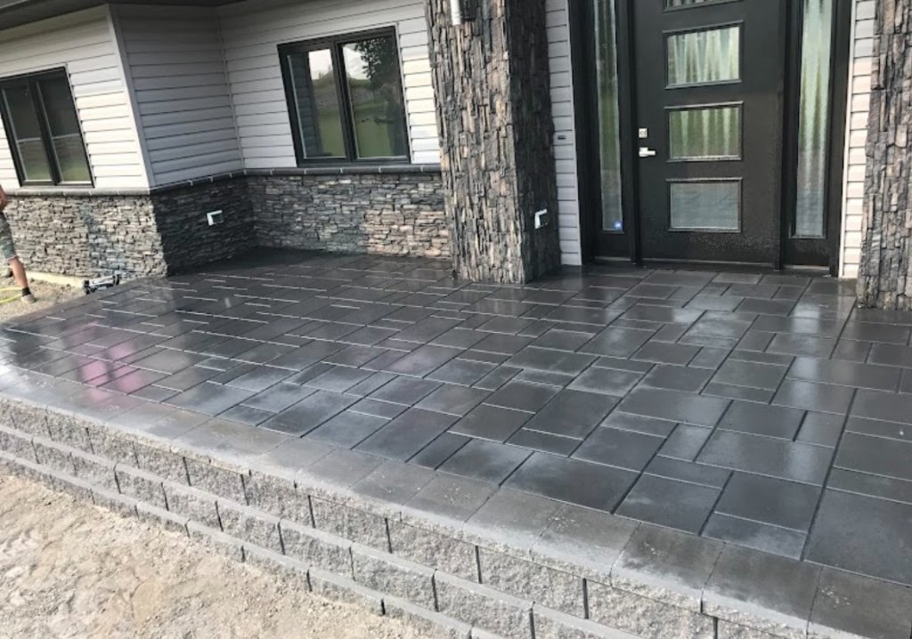 Large curved grey paving stone patio with fire pit opening