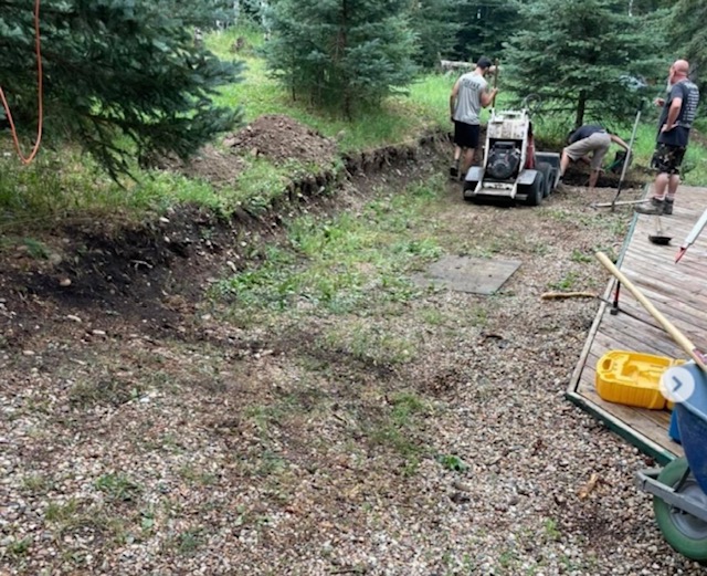 Landscape preparation work with equipment and crew in yard